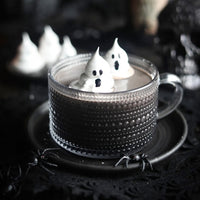 Cup of dark hot chocolate with ghost-shaped marshmallows on a dark background