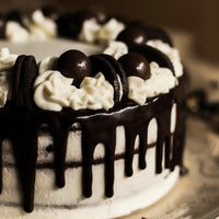 Chocolate cake with white frosting, chocolate drizzle, and Oreo cookies on a blurred background