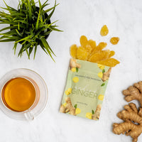 Candied Ginger - bag opened and spilling out on a white counter next to ginger tea and ginger