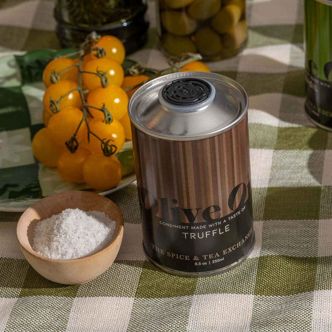 Truffle Extra Virgin Olive Oil next to bowl of salt, yellow mini tomatoes, and olives